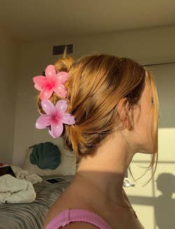 reviewer using pair of pink flower clips to hold up updo