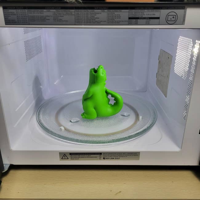 Green dinosaur-shaped mug successful  a microwave with a solid  turntable inside