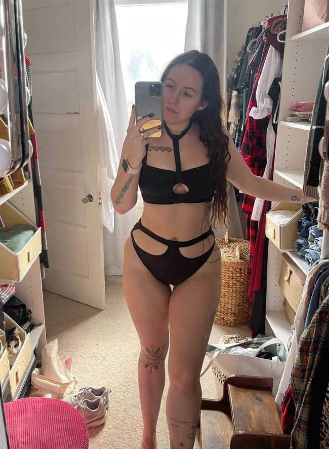 Writer is wearing the black bikini set, with a choker and cut out features