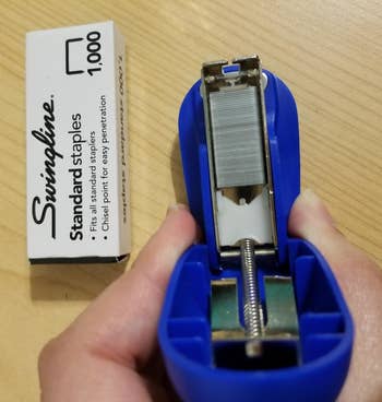 the mini blue stapler opened to see the staples inside, next to a box of 1000 staples