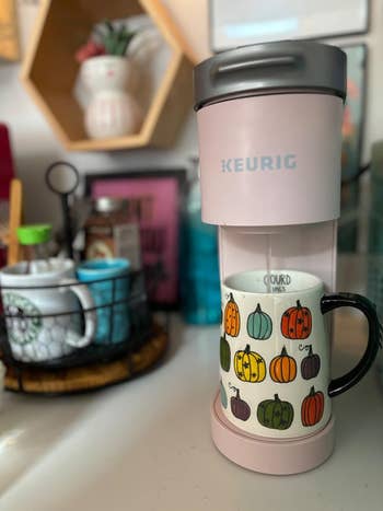 Keurig java  shaper  brewing java  into a mug adorned with colorful pumpkin designs, acceptable   connected  a room  antagonistic  with assorted  accessories