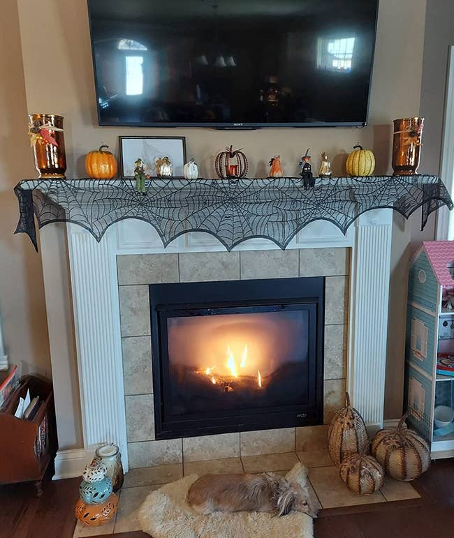 the black spiderweb mantel scarf on a fireplace mantel with other halloween decor sitting on top
