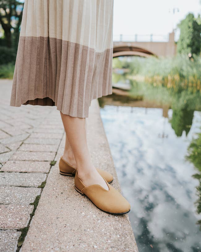 person wearing light brown flats with a skirt