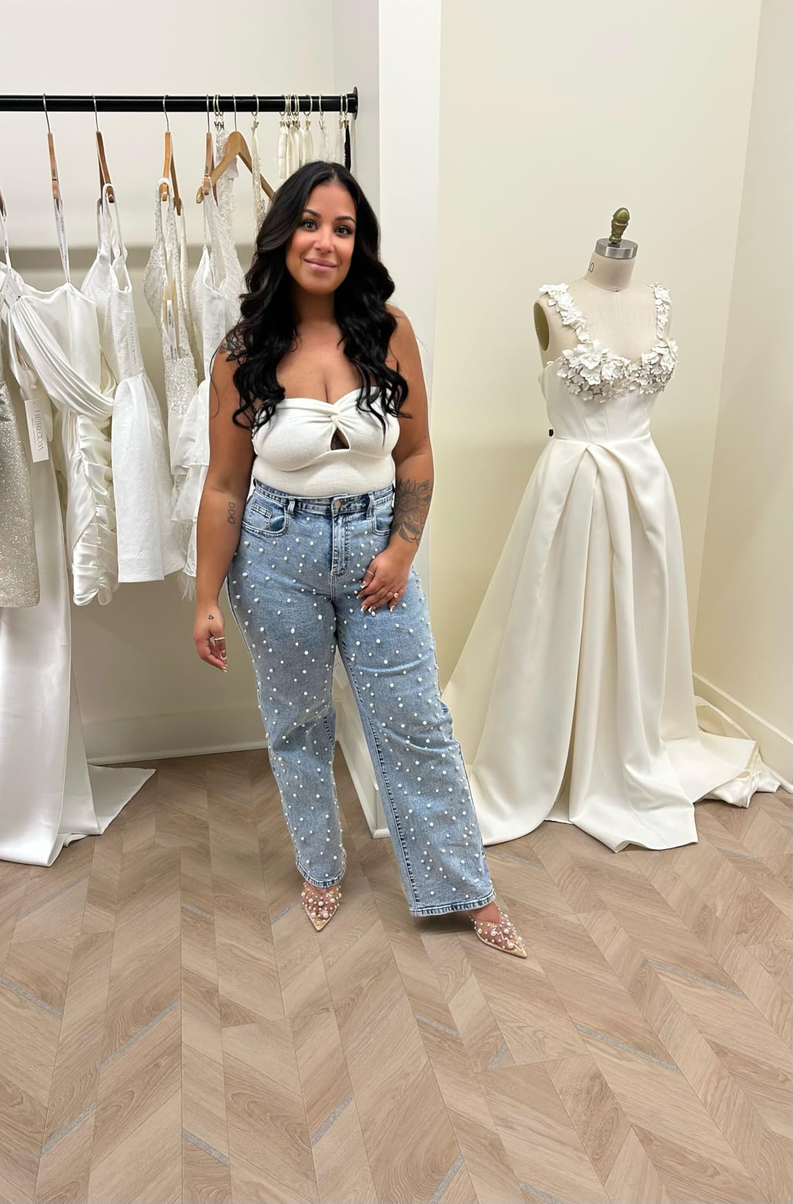 Person successful  pearl-embellished jeans and achromatic  apical  stands successful  a bridal boutique adjacent  to a mannequin wearing an elegant achromatic  wedding dress