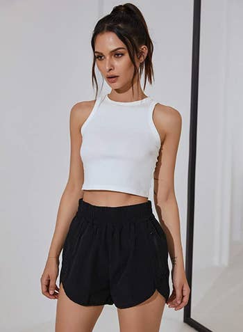 model wearing shorts in black with cropped white tank