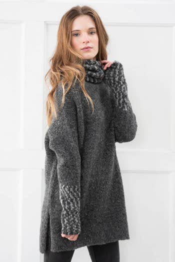 a model wearing a long hand knit sweater 