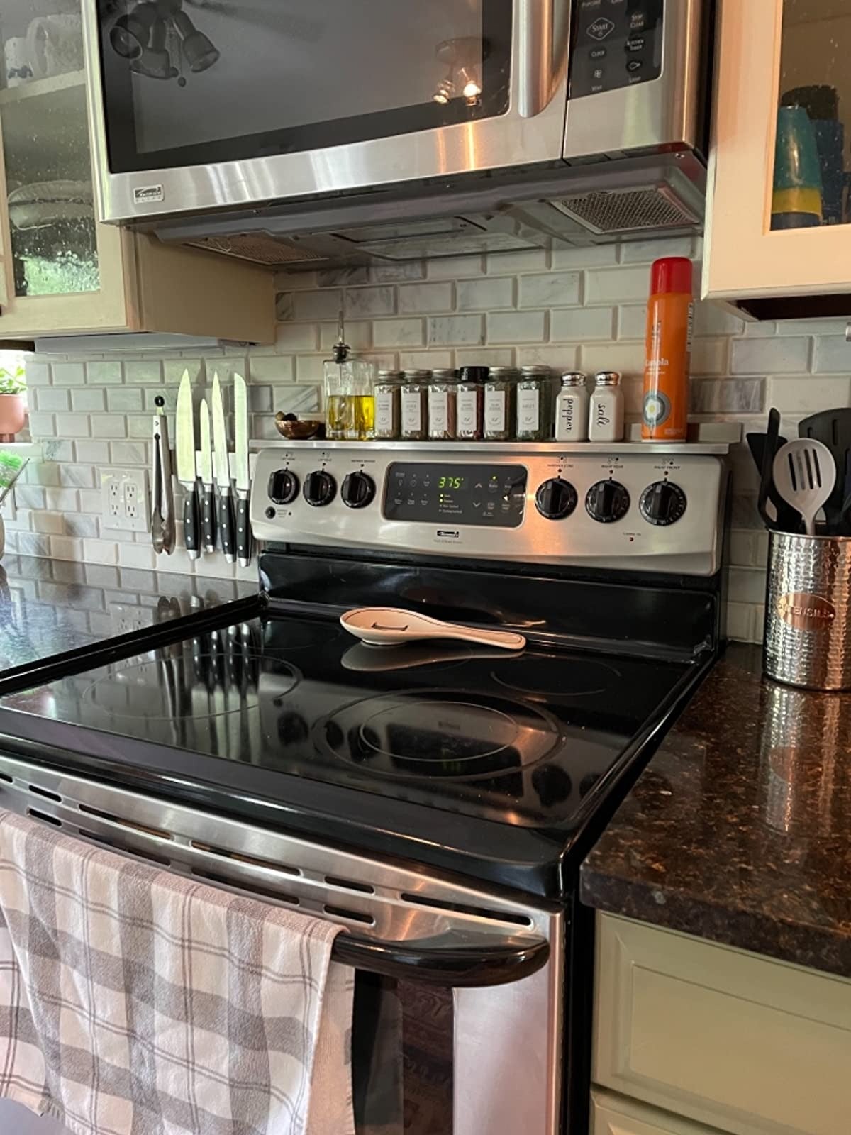 silver stove shelf with various spice jars above electric stovetop in kitchen