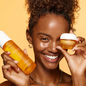 model holding essence bottle near face