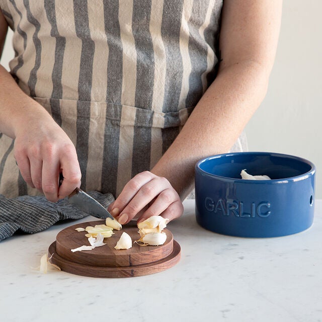 a person chopping garlic on a garlic house top, next to the garlic house