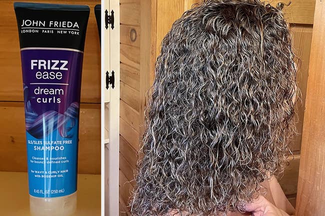 Reviewer image of blue, purple, and black bottle of shampoo on top of a white counter, reviewer's brown tightly curled hair after using product, standing in front of wooden door