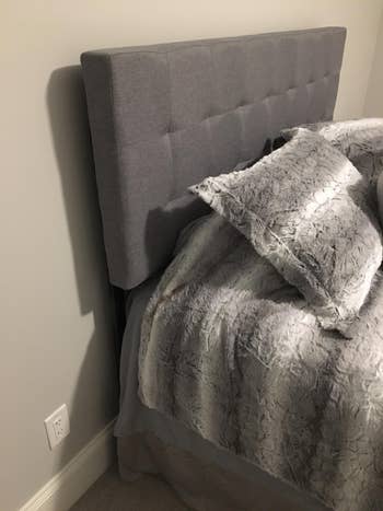 Reviewer image of side-view of product with blankets and pillows on bed pushed against wall