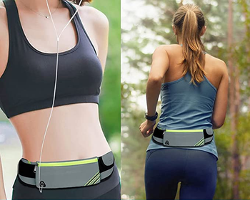 Model wearing gray slim fanny pack around waist in the front and back with phone inside main compartment