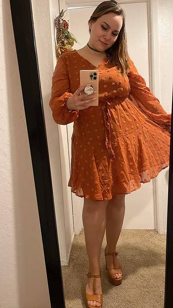 A reviewer wearing the dress in orange 