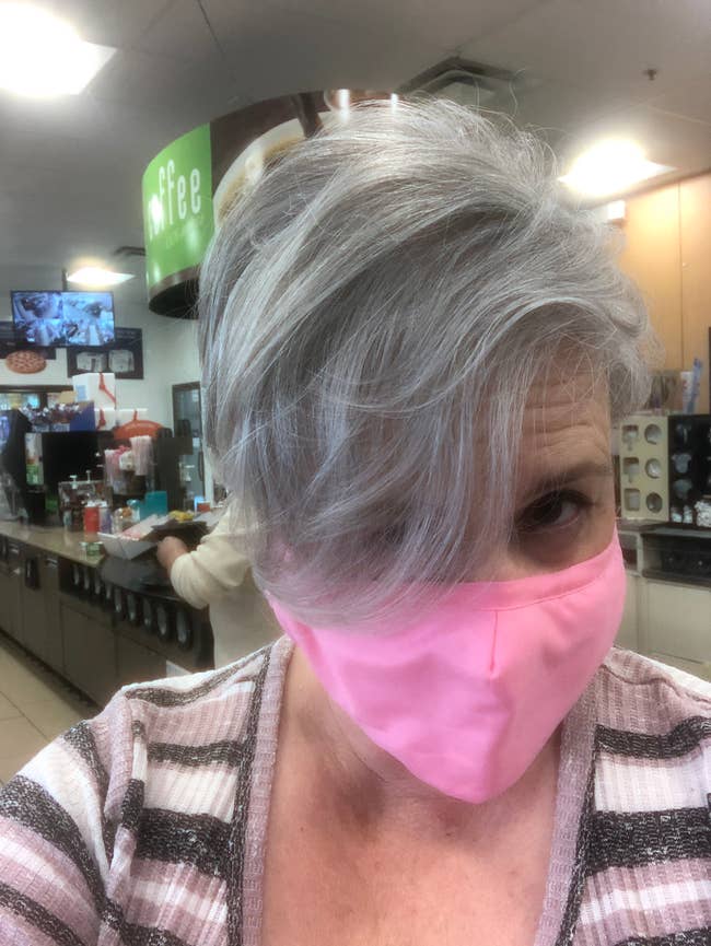 Person with abbreviated hairsbreadth wearing a pinkish disguise successful a java shop, looking astatine the camera