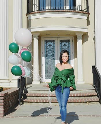 reviewer in green off-shoulder wrap top and blue jeans
