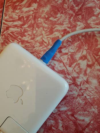reviewer image of the moldable glue in black around an Apple laptop cord