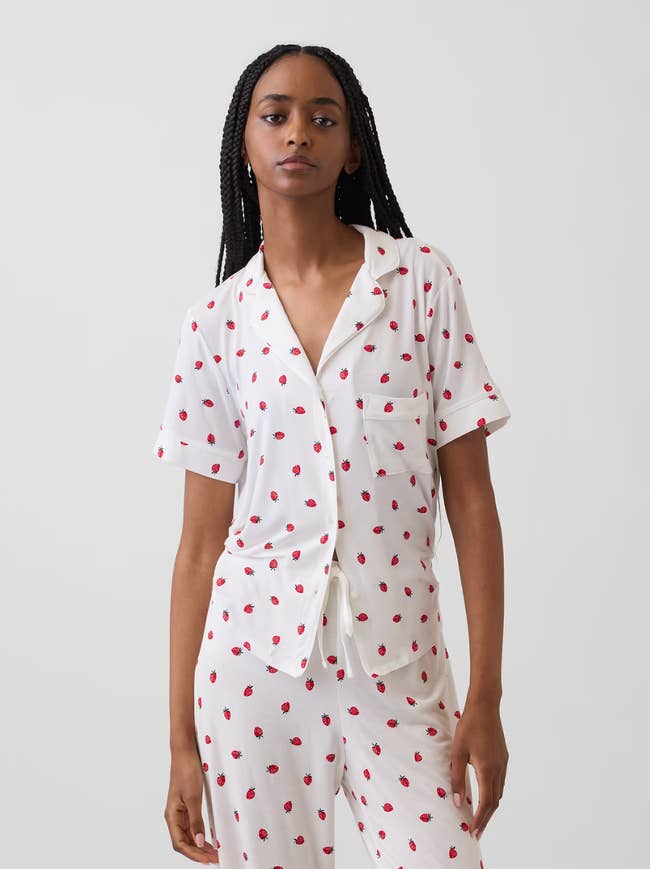 Person wearing a matching pajama acceptable   with tiny  cherry patterns, featuring a short-sleeve button-up shirt