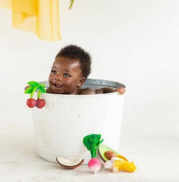 baby inside water bucket with the toys around them 