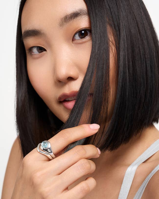 Model with bob haircut displays a stylish metallic  ringing  with a bluish  gemstone, enhancing a modern   and elegant appearance