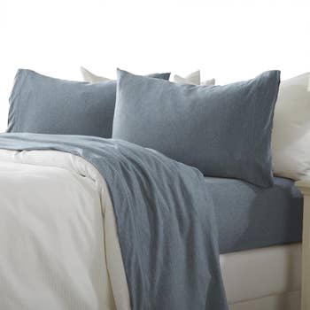 A neatly made bed featuring a set of soft textured blue bedding
