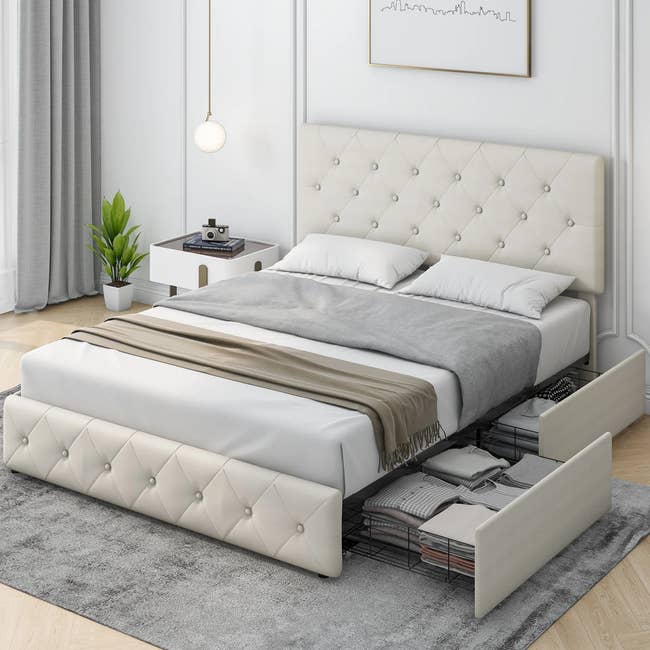the off-white tufted platform bed with two bottom storage drawers open 