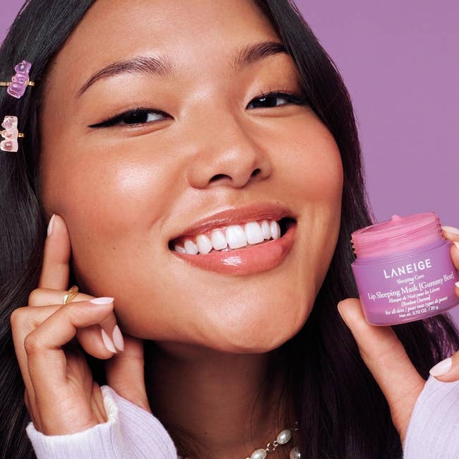 Model smiling and holding a Laneige articulator  sleeping disguise  container, showcasing skincare merchandise  for a quality   buying  article