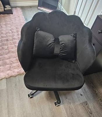 Plush, petal-shaped black chair with a matching bow-shaped cushion, perfect for a stylish home office or vanity setup