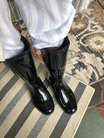 reviewer POV photo wearing shiny black tall rainboots