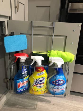 Cleaning supplies organized wrong a furniture door, including Windex, Lysol, Clorox sprays, and microfiber cloths connected a doorway rack