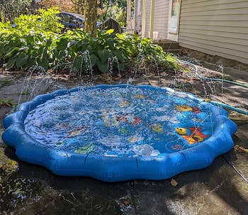 Inflatable splash pad in a backyard connected to a garden hose 