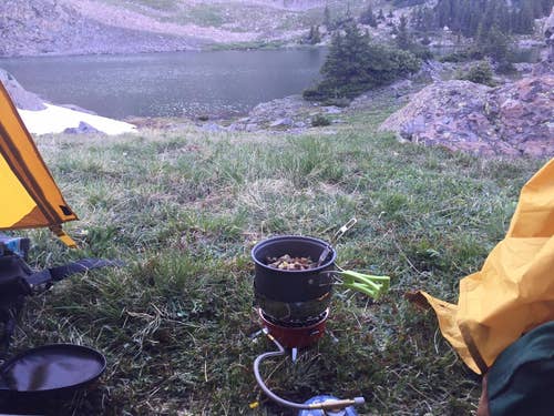 reviewer photo cooking with the pot on camp stove, overlooking river