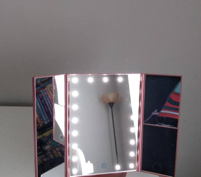 a reviewer photo of the illuminated. mirror in pink 