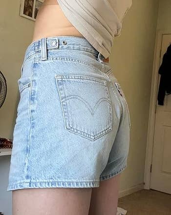 Person wearing high-waisted denim shorts in a casual indoor setting