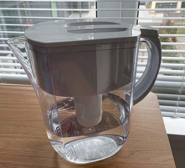 reviewer's clear pitcher with a white top filled with water