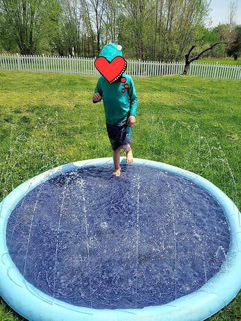 reviewer photo of a young child playing on the circle splash pad