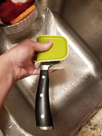 reviewer using the same scrubber to clean a chef's knife over a sink
