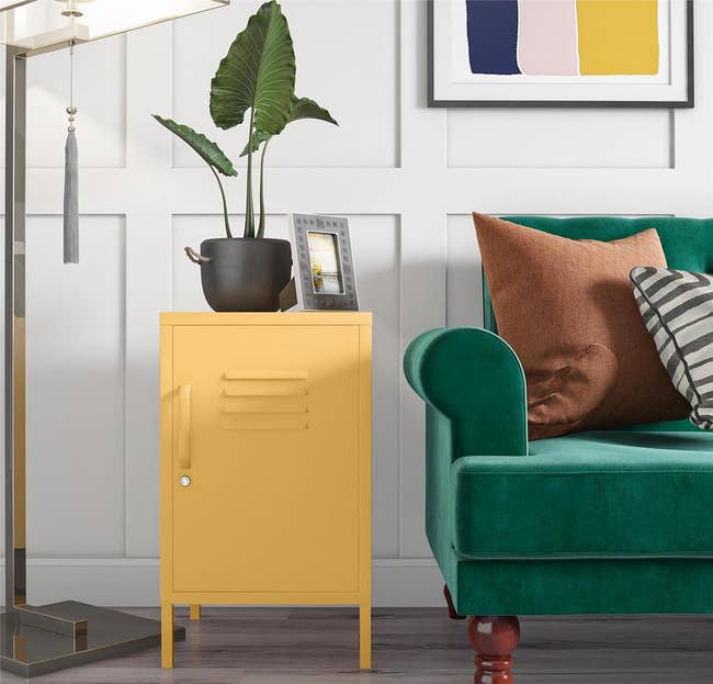 a yellow locker side table sitting next to a green couch 