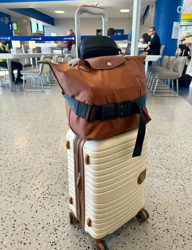 a brown bag strapped to the top of a suitcase