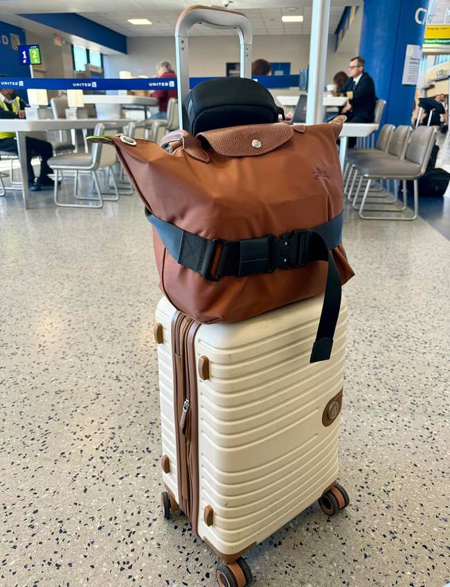a brown bag strapped to the top of a suitcase