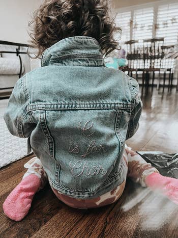 a child wearing a denim jacket that says 
