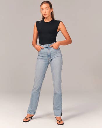 front of model wearing the high waisted blue jeans with a black tank top and heels