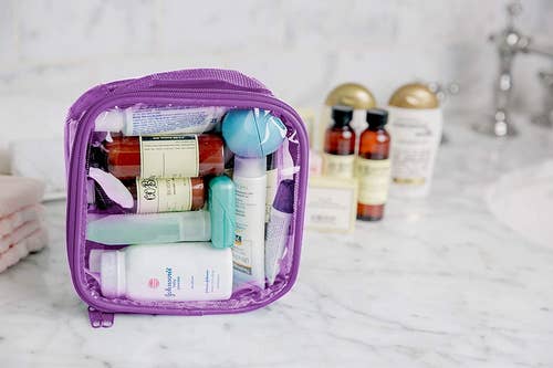 the lilac toiletry bag on a bathroom counter full of several items 