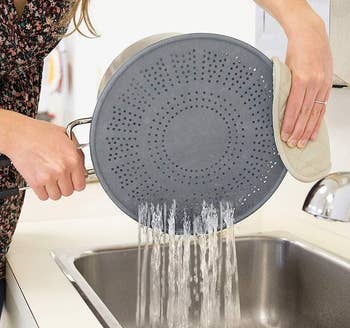 a model using the splash guard as a strainer and pouring water into a sink 
