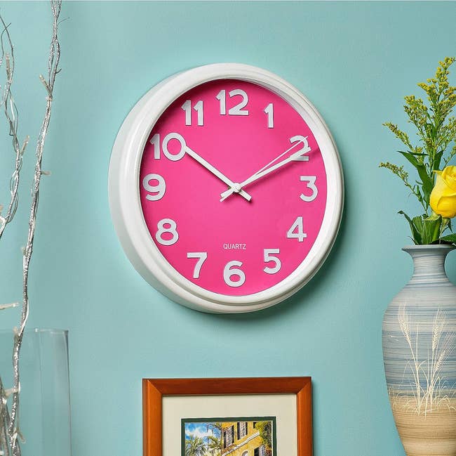 White round clock with hot pink face and white numbers 