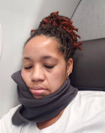 reviewer sleeping on plane while wearing the pillow
