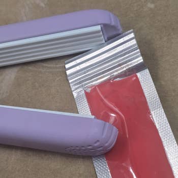 A purple bag sealer next to a red foil packet