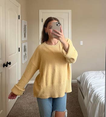 Person taking a reflector  selfie, wearing a cozy, oversized sweater and ripped jeans successful  a casual chamber  setting