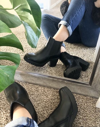 reviewer photo of them wearing black platform booties and showing them off in the reflection of their mirror