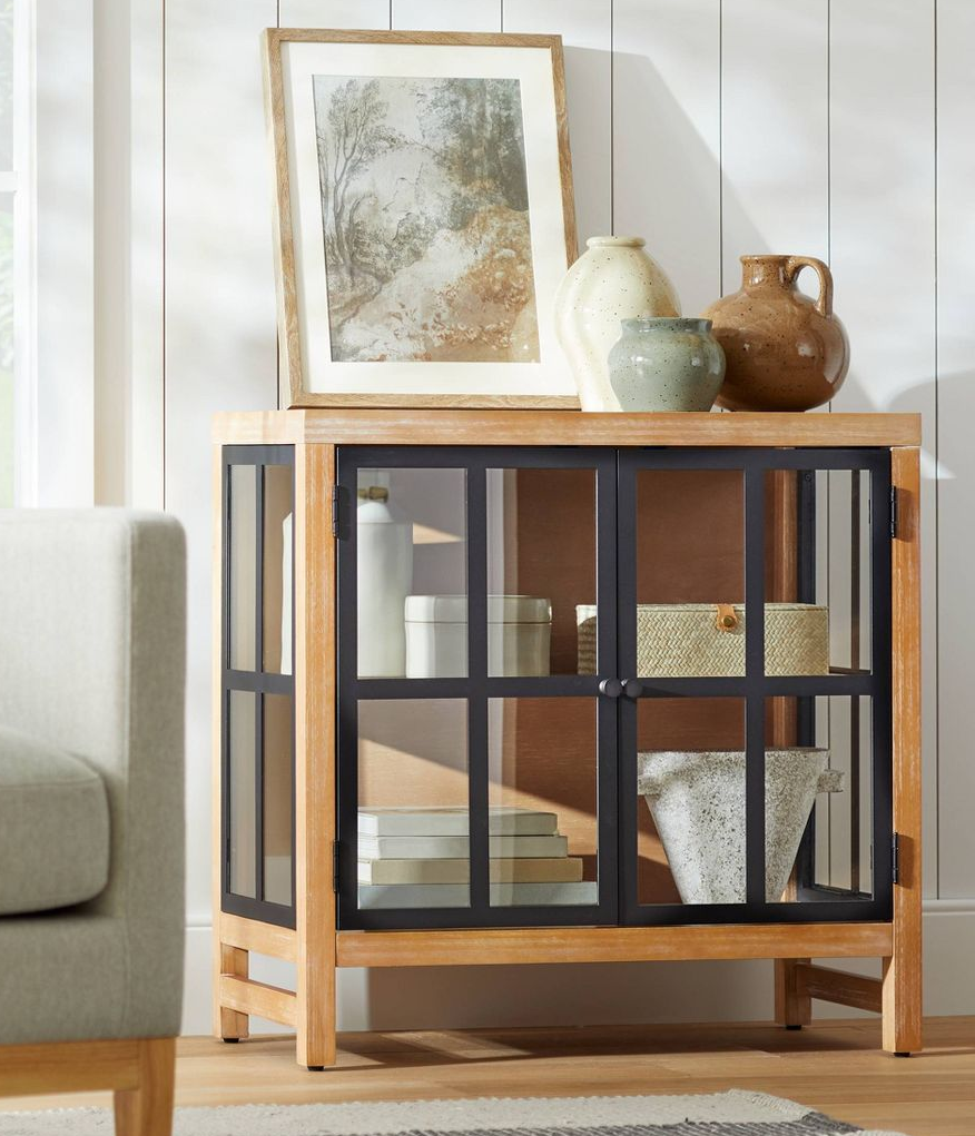 the wood two-tier cabinet with black window pane-style doors