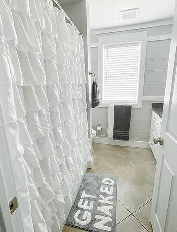 reviewer side-view photo of the white ruffled shower curtain in their bathroom